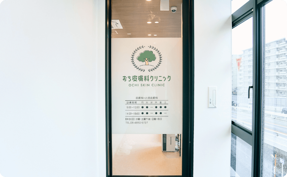 おち皮膚科クリニック入口のガラスドア（診療時間と電話番号の掲示）